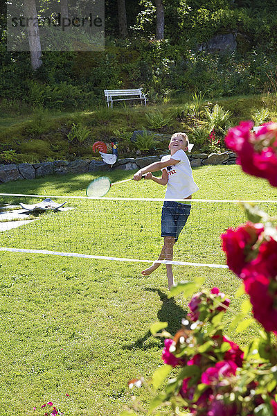 Junge spielt Badminton im Garten