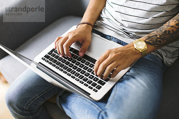 Teenager-Junge sitzt auf der Couch zu Hause mit Laptop  Teilansicht