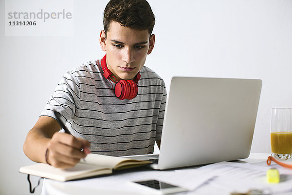Teenager-Junge macht Hausaufgaben mit Laptop