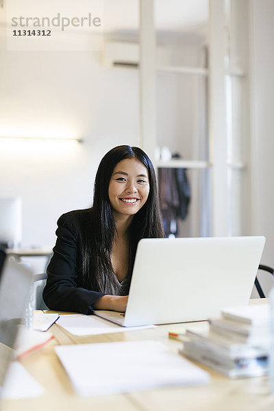 Junge Asiatin arbeitet im Büro mit Laptop
