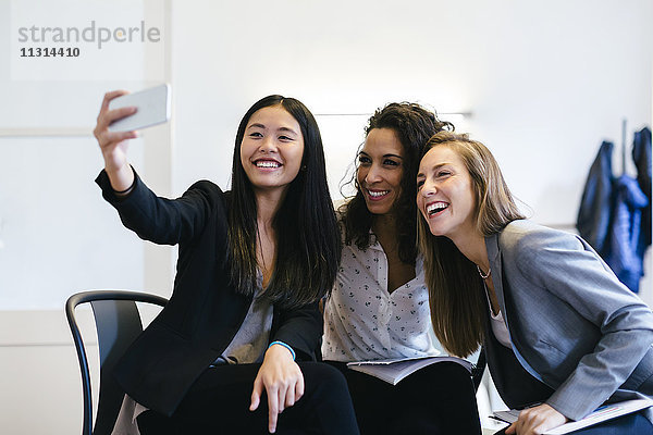 Drei Geschäftsfrauen  die sich mit einem Smartphone selbstständig machen