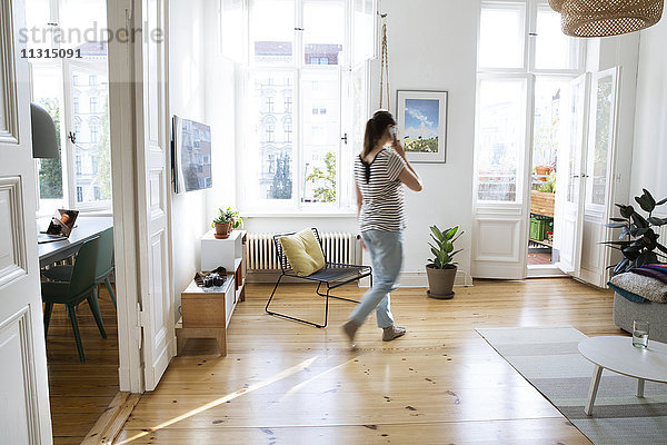 Frau zu Hause spricht am Handy