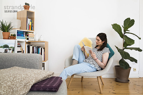 Frau zu Hause sitzend auf Stuhl Lesebuch