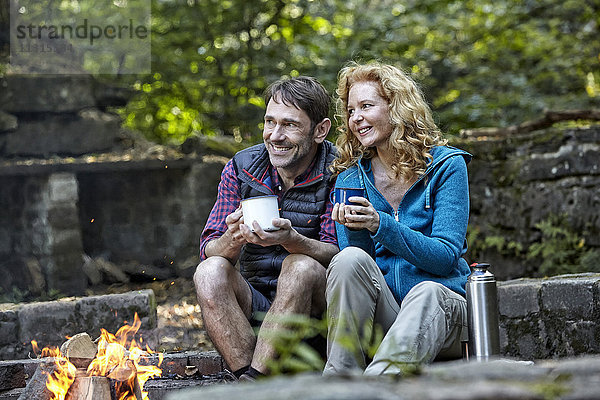 Glückliches Paar sitzt am Lagerfeuer