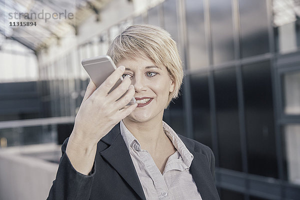 Porträt einer lächelnden  blonden Geschäftsfrau mit Handy