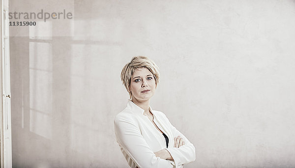 Porträt einer blonden Geschäftsfrau mit gekreuzten Armen