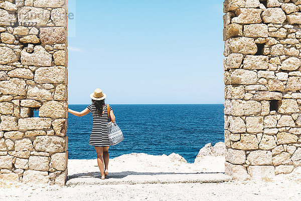 Griechenland  Milos  Firopotamos Strand  Frau steht in der Tür in der Steinmauer  Blick in die Ferne