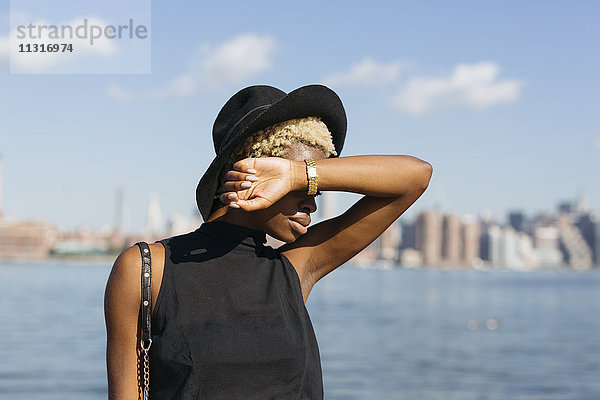 USA  New York City  Brooklyn  junge Frau mit Hut am East River
