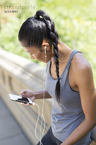 Sportlerin beim Musikhören mit dem Smartphone