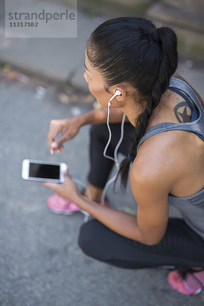 Sportlerin beim Musikhören mit dem Smartphone