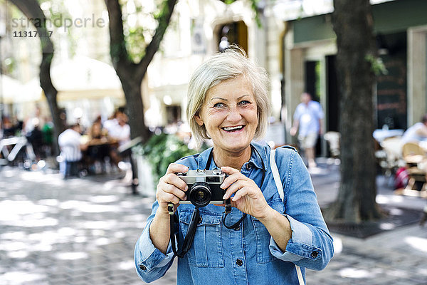 Porträt einer lächelnden Seniorin mit Kamera