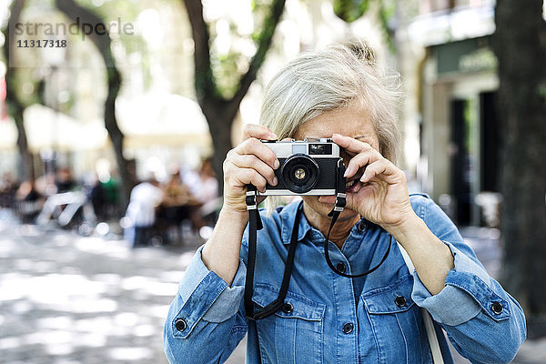 Seniorin beim Fotografieren mit der Kamera