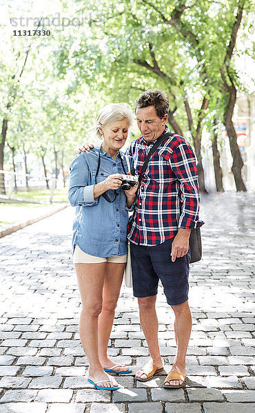 Seniorenpaar in Shorts und Flip-Flops mit Blick auf die Kamera