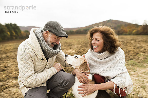 Glückliches Seniorenpaar mit Hund in der Natur