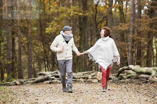 Seniorenpaar geht Hand in Hand im Wald spazieren