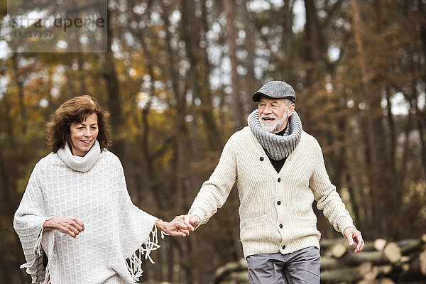 Seniorenpaar geht Hand in Hand im Wald spazieren