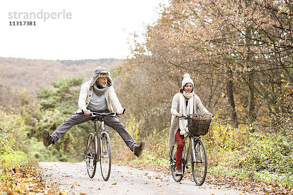 Seniorenpaar bei einer Fahrradtour mit Hund im Herbst