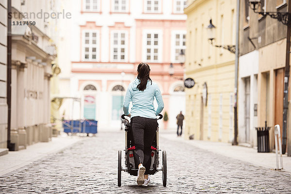 Frau läuft mit Kinderwagen in der Stadt