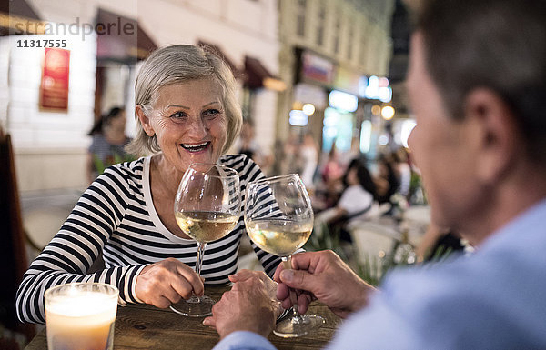 Seniorenpaar trinkt Wein an einer Bar im Freien