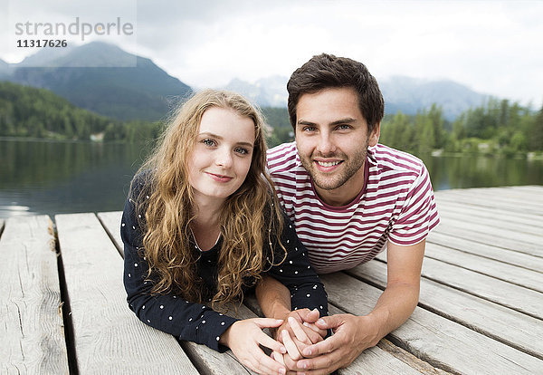 Verliebtes junges Paar liegt am Steg am See
