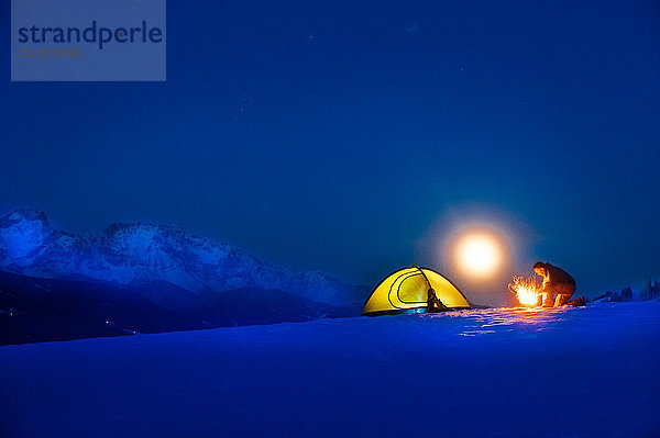 Seniorencamping in verschneiter Landschaft bei Vollmond