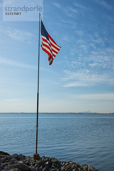USA  New York  Queens  Jamaica Bay  amerikanische Flagge an der Jamaica Bay mit Blick auf New York City