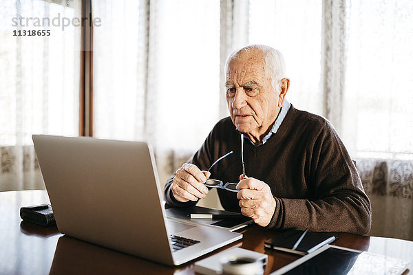 Senior-Fotograf mit Blick auf den Laptop zu Hause