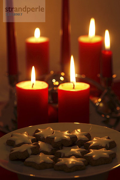 Beleuchtete Kerzen und Teller mit Zimtsternen