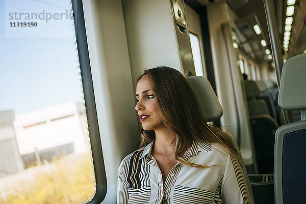 Frau im Zug mit Blick aus dem Fenster
