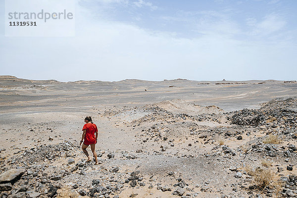 Marokko  Merzouga  Frau  die durch die Steinwüste läuft