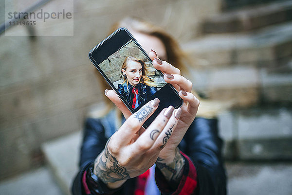 Tätowierte Frauenhände nehmen Selfie mit Smartphone  Nahaufnahme