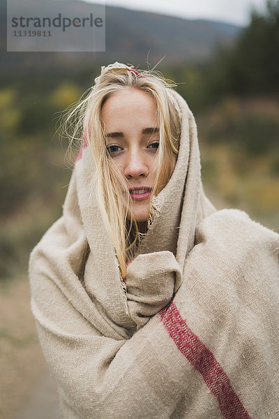 Porträt einer jungen Frau in einer Decke im Freien