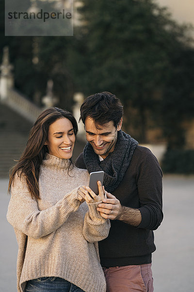 Lachendes Paar schaut auf Handy