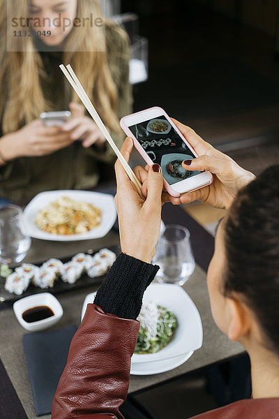 Frau fotografiert Sushi in einem Restaurant  Teilansicht
