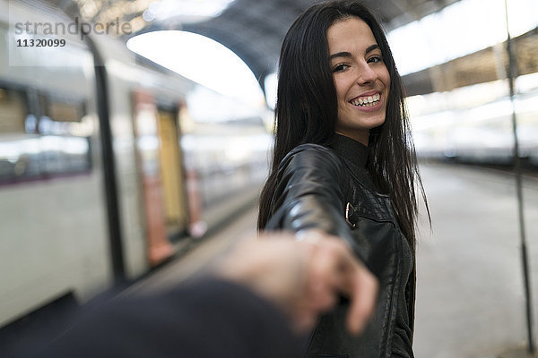 Glückliche junge Frau hält Hand am Bahnhof