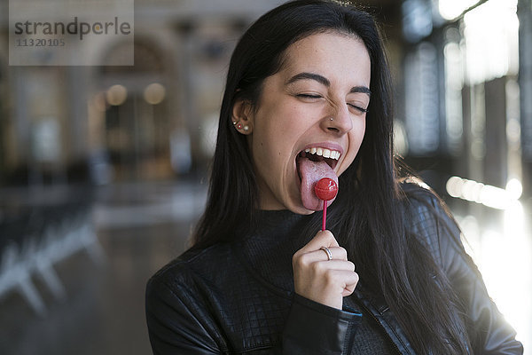 Porträt einer jungen Frau mit Lollipop ziehenden Gesichtern