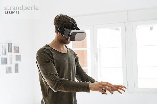 Junger Mann mit Virtual-Reality-Brille zu Hause