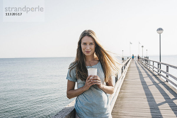 Porträt einer glücklichen jungen Frau mit Kaffee zum Anlegesteg
