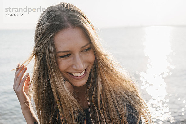 Porträt einer glücklichen jungen Frau vor dem Meer