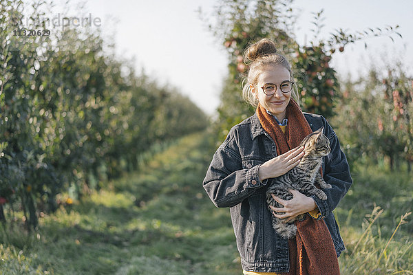 Junge Frau mit einer Katze im Apfelgarten