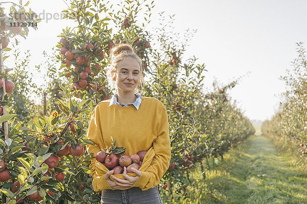 Junge Frau mit Äpfeln im Obstgarten