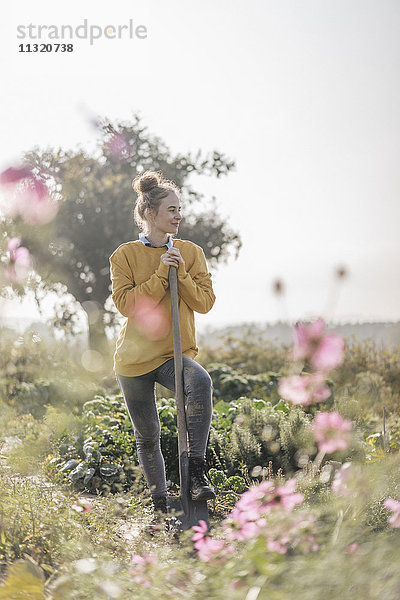 Junge Frau mit Spaten im Bauerngarten