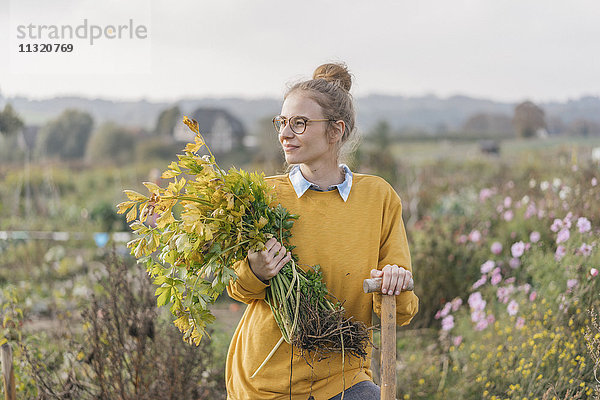 Junge Frau hält Pflanze im Bauerngarten