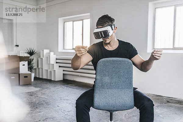 Mann sitzend auf Stuhl im leeren Loft mit VR-Brille