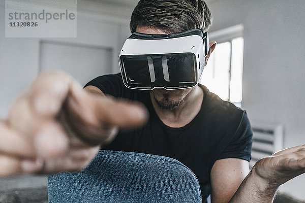 Mann auf Stuhl sitzend mit VR-Brille