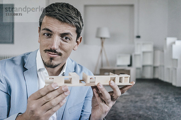 Porträt eines selbstbewussten Geschäftsmannes mit Architekturmodell