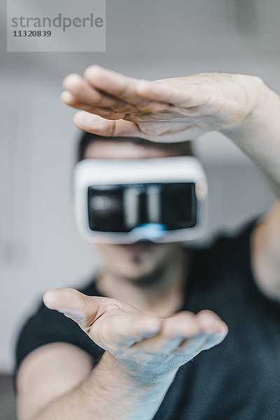 Mann mit erhobenen Händen mit VR-Brille