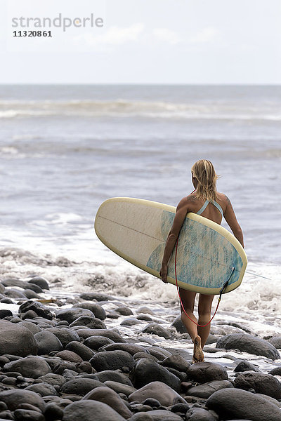Indonesien  Bali  Frau mit Surfbrett am Meer
