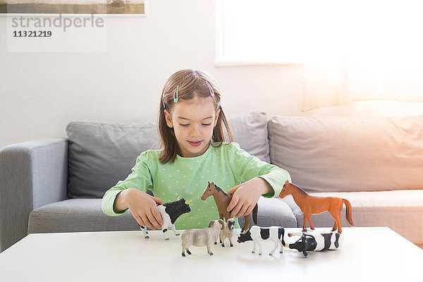 Kleines Mädchen spielt zu Hause mit Tierfiguren