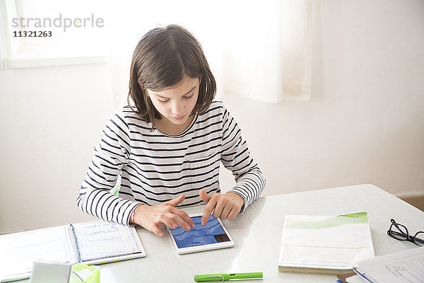 Mädchen macht Hausaufgaben mit Tablette